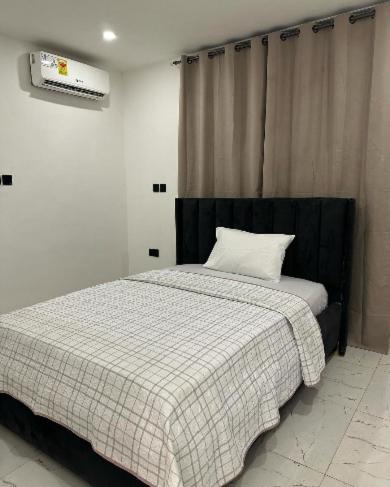 a bedroom with a bed with a black and white blanket at REOs Smart Haven with Pool in Oblogo