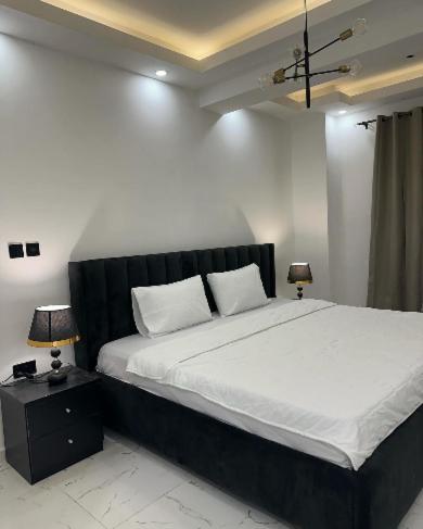 a bedroom with a large bed and two lamps at REOs Smart Haven with Pool in Oblogo