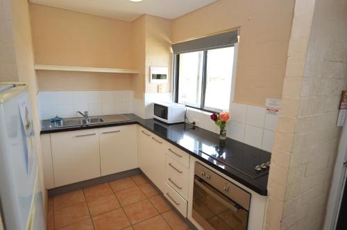 a small kitchen with a sink and a microwave at Riverview Holiday Apartment 65 - Kalbarri WA in Kalbarri
