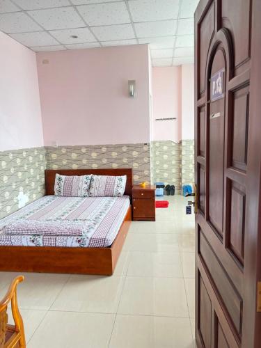 ein Schlafzimmer mit einem Bett und einer Tür in einem Zimmer in der Unterkunft KHÁCH SẠN HOÀNG TRÍ 89 (HOANG TRI 89 HOTEL) in Hố Nai
