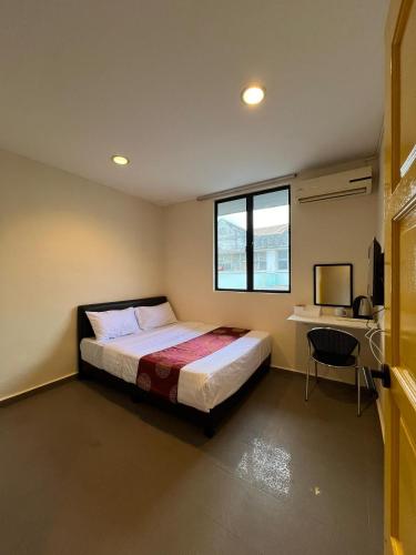 a bedroom with a bed with a desk and a window at Jb Sojourn in Skudai