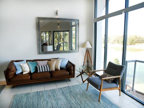 a living room with a brown leather couch and a mirror at Sunrise Cove Holiday Apartments by Kingscliff Accommodation in Kingscliff