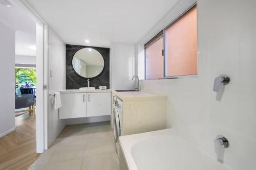 a white bathroom with a sink and a mirror at Stylish 2BR Unit in Southport in Gold Coast