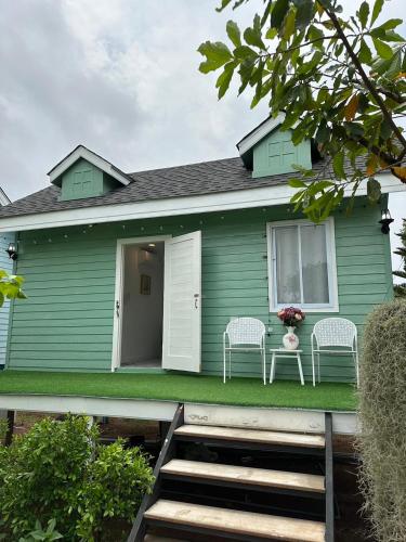 a green house with two chairs on the front porch at Peang Tara Cafe & Resort in Nong Khai