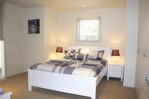 Cama blanca en habitación blanca con 2 lámparas en Lonsdale Shores, en Point Lonsdale