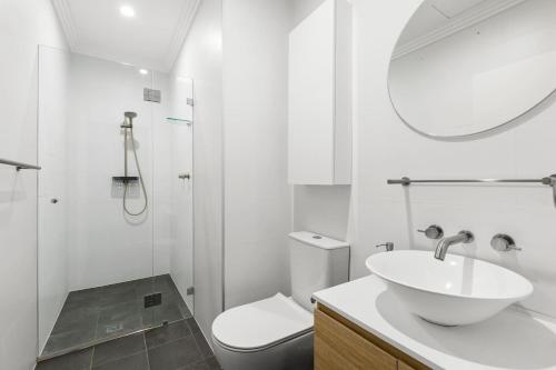 a bathroom with a sink and a toilet and a mirror at 'Laube 105' Modern Inner-city Sanctuary with Balcony in Sydney