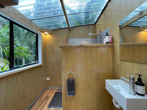 a bathroom with a sink and a mirror and a window at Tui Cottage - Waiheke Escapes in Onetangi