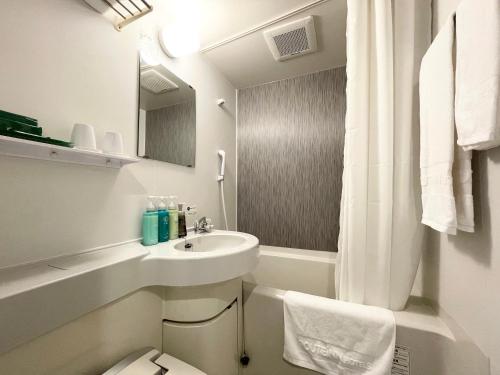 Baño blanco con lavabo y aseo en Hotel Route-Inn Yuki, en Yuki