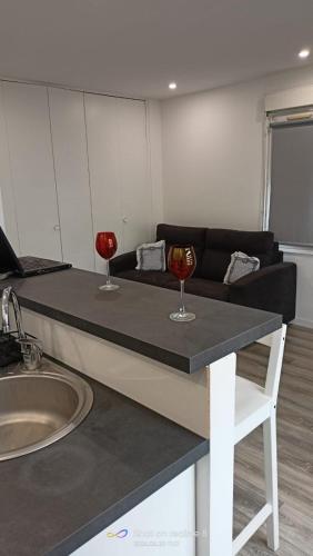una sala de estar con sofá y 2 copas de vino en una mesa en Studio à 15 min du stade de France et de la gare du Nord, en Sarcelles