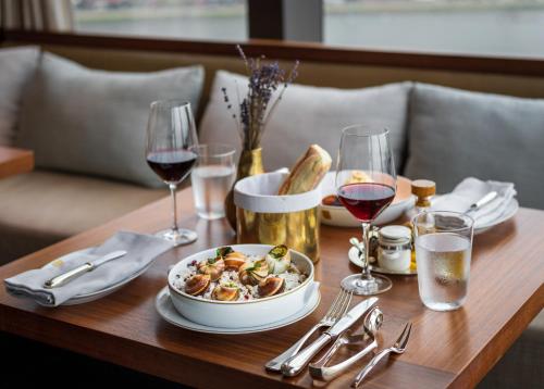 a table with a bowl of food and glasses of wine at Rosewood Phnom Penh in Phnom Penh