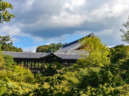 a building with a roof surrounded by trees at REF Kyoto Hachijoguchi by VESSEL HOTELS in Kyoto