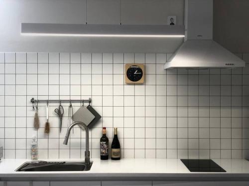 a kitchen with a sink and a white tiled wall at Josuri& in Jeju