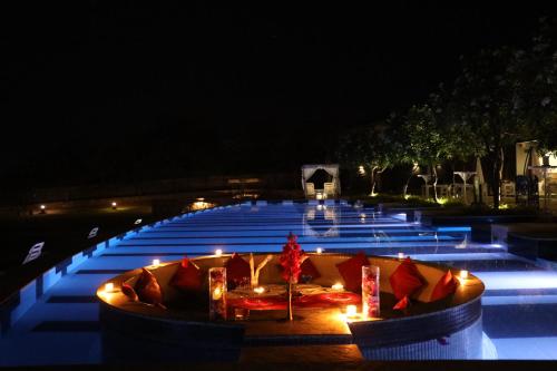 a pool at night with lights in the middle at TatSaraasa Resort & Spa, Udaipur in Udaipur