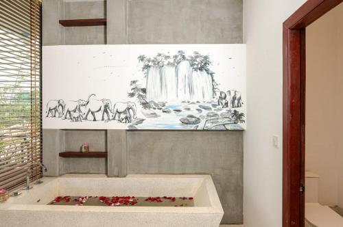 a bathroom with a bath tub with a painting on the wall at Victoria Central Residence in Siem Reap