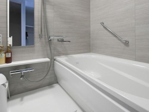 a bathroom with a white tub and a shower at Vessel Inn Shigamoriyama Station in Moriyama