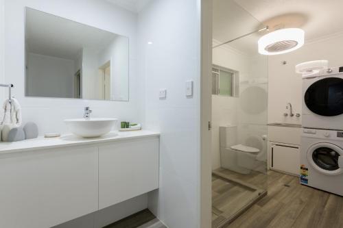 a white bathroom with a sink and a washing machine at Marina Terraces Port Douglas in Port Douglas