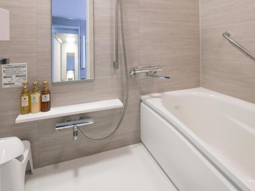 a bathroom with a shower and a tub and a sink at Vessel Inn Shigamoriyama Station in Moriyama