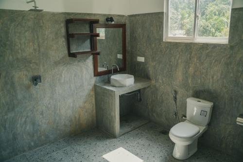 a bathroom with a toilet and a sink and a mirror at Leyon Paradise Hotel in Unawatuna
