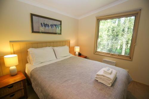 a bedroom with a bed with two lamps and a window at Alpine Arnica Cottage 2 in Harrietville