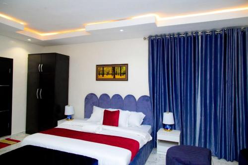 a bedroom with a large bed and blue curtains at D2 Studio Apartment in Lagos