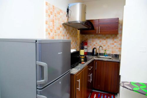 a kitchen with a stainless steel refrigerator and wooden cabinets at D2 Studio Apartment in Lagos