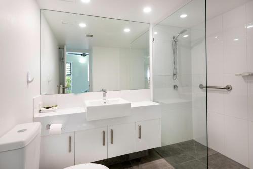 a white bathroom with a sink and a mirror at Marlin Cove Holiday Resort in Trinity Beach