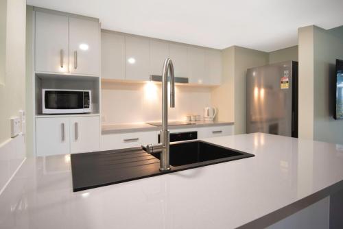 a kitchen with white cabinets and a stainless steel refrigerator at Marlin Cove Holiday Apartments in Trinity Beach
