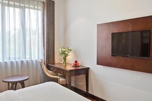 Habitación de hotel con cama y escritorio con TV. en 22Land Residence Hotel&Spa Ha Noi en Hanoi