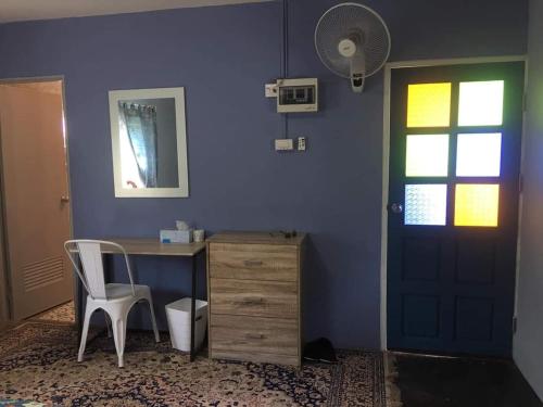 Habitación con escritorio y pared azul con puerta. en Giardino Di San Sai en Chiang Mai