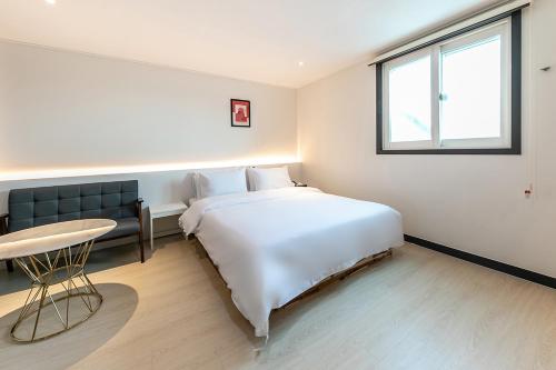 a bedroom with a bed and a table and a window at Hotel Yaja Terminal Branch in Jeonju