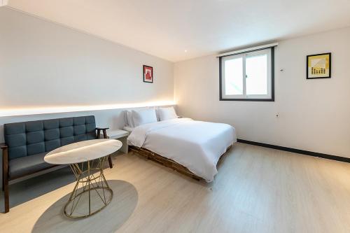 a bedroom with a bed and a couch and a table at Hotel Yaja Terminal Branch in Jeonju
