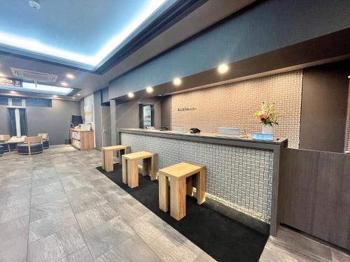a restaurant with a counter with benches and tables at Hotel Route-Inn Nagaoka Ekimae in Nagaoka