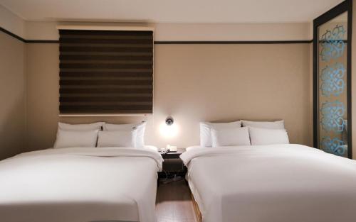 two beds sitting next to each other in a room at Hotel Yaja Terminal Branch in Jeonju