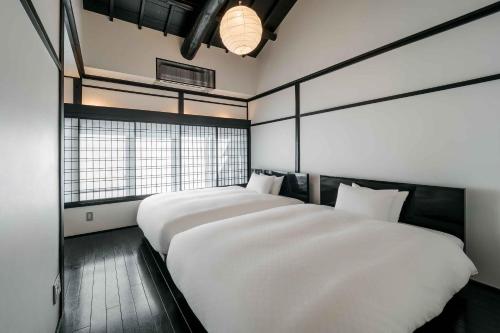 a bedroom with two white beds and a window at Shobu an Machiya House in Kyoto