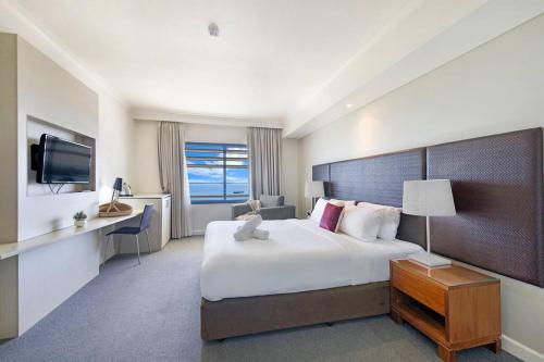 a hotel room with a large bed and a television at Sky-high Waterfront Living across Two Apartments in Darwin