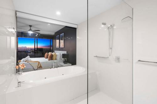 uma casa de banho com banheira e uma cama com espelho em No Parking - Converted Two Bedroom Apartment - Amazing Hinterland Views - Circle on Cavill - Wow Stay em Gold Coast