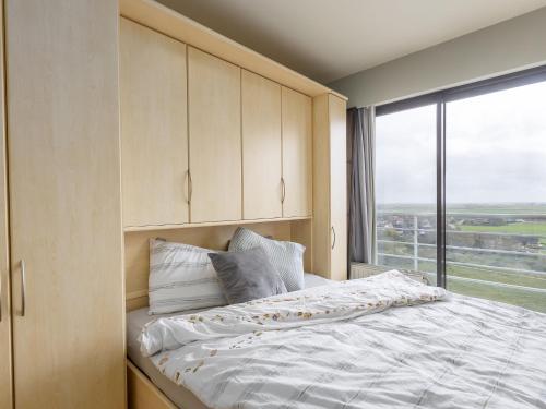 een slaapkamer met een bed met een groot raam bij Apartment on the 8th floor with terrace in Middelkerke