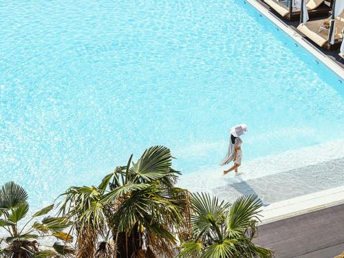 Eine Frau mit einem Regenschirm, die entlang eines Schwimmbads geht. in der Unterkunft Latterace Resort in Yeosu