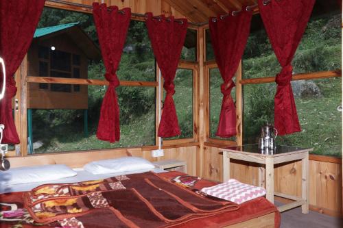 - une chambre avec un lit et une fenêtre avec des rideaux rouges dans l'établissement Trekking Cougars Huts, à Dharamshala