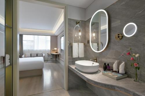 y baño con cama, lavabo y espejo. en Mercure Shenzhen Nanshan en Shenzhen