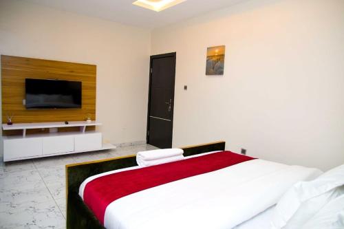U2 One Bedroom Apartment في لاغوس: غرفة نوم بسرير كبير وتلفزيون بشاشة مسطحة