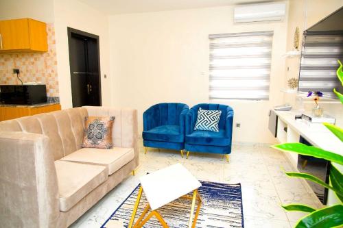 ein Wohnzimmer mit einem Sofa und zwei blauen Stühlen in der Unterkunft U2 One Bedroom Apartment in Lagos
