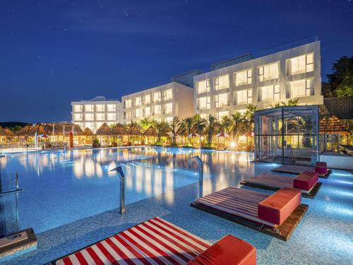 a hotel with a large swimming pool at night at Yeosu Calacatta Hotel & Resort in Yeosu