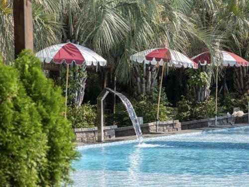 a swimming pool with a fountain and two umbrellas at Yeosu Calacatta Hotel & Resort in Yeosu