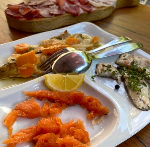 a plate of food with fish and a spoon and lemon at Agriturismo La Vecchia Chioderia in Grandola ed Uniti