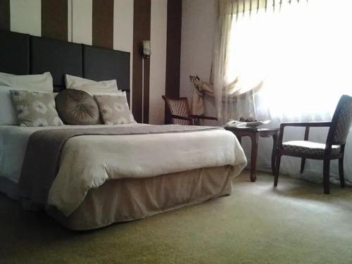 1 dormitorio con 1 cama grande, mesa y sillas en Leopards road room en Lusaka