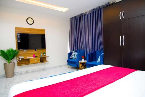 a bedroom with a bed and two blue chairs and a tv at U3 Studio Apartment in Lagos