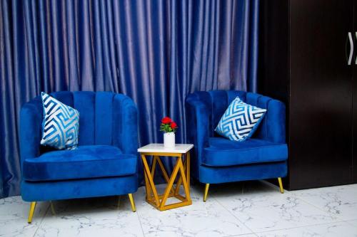 two blue chairs and a table with a vase of flowers at U3 Studio Apartment in Lagos