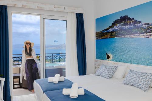 a woman standing in a bedroom with a view of the ocean at Hotel Ziakis in Pefki