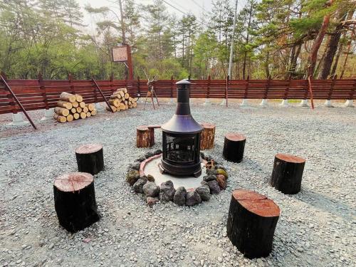 a small stove in the middle of some logs at 団体歓迎ジョイサウンドカラオケ付き北軽井沢超大型貸別荘7寝室5浴室20人泊まれる in Karuizawa